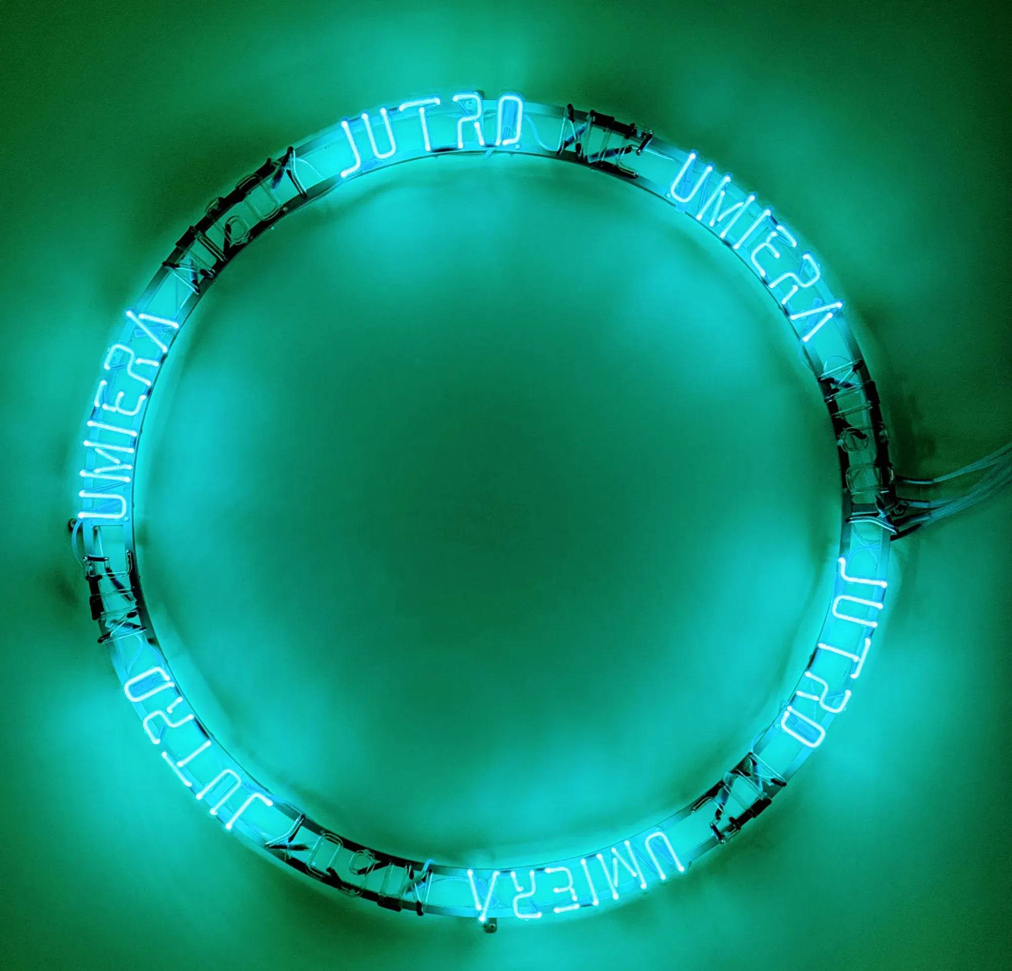 Circular turquoise neon sign reading 'Jutro nie umiera nigdy' at the Neon Side Gallery in Wroclaw.