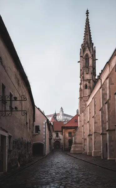 Cobblestone street in Bratislava's Old Town with Bratislava Castle in the background.