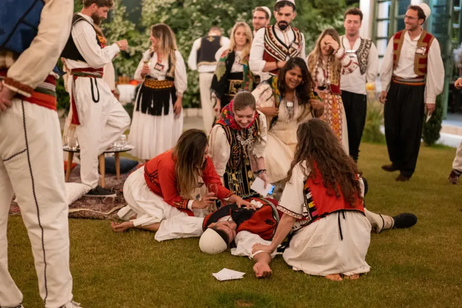 A group in traditional Balkan attire participates in a lively cultural performance.