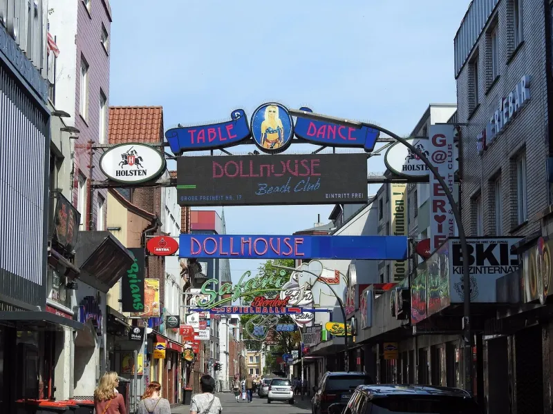 A vibrant street scene in a German city, filled with neon signs and advertisements.