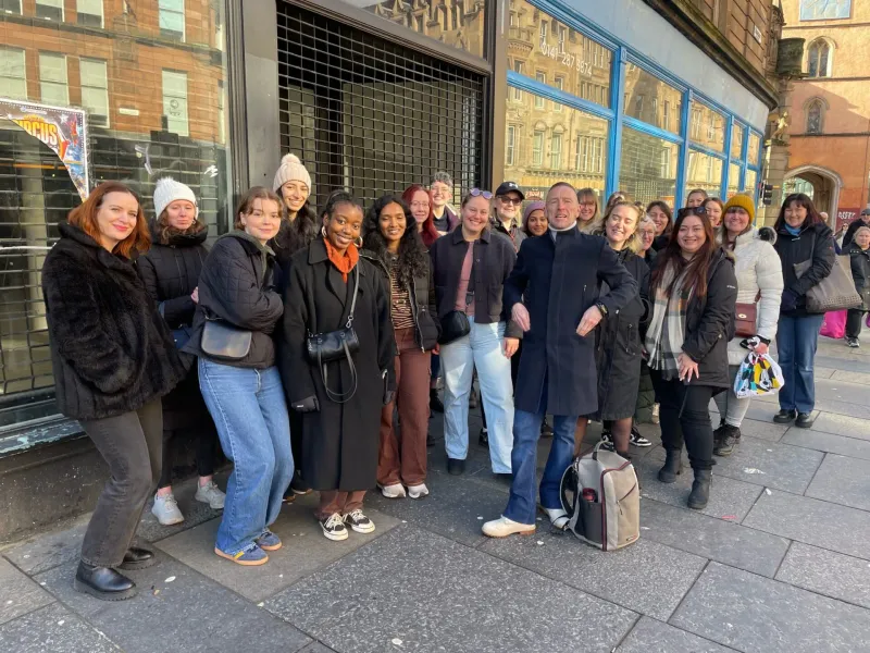 A large tour group enjoys a walking tour in Glasgow, Scotland.
