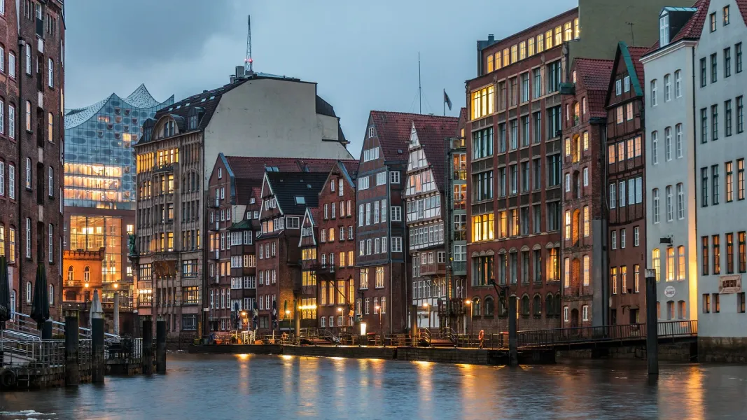 Historic Hamburg Speicherstadt at night, illuminated buildings reflected in the canal.