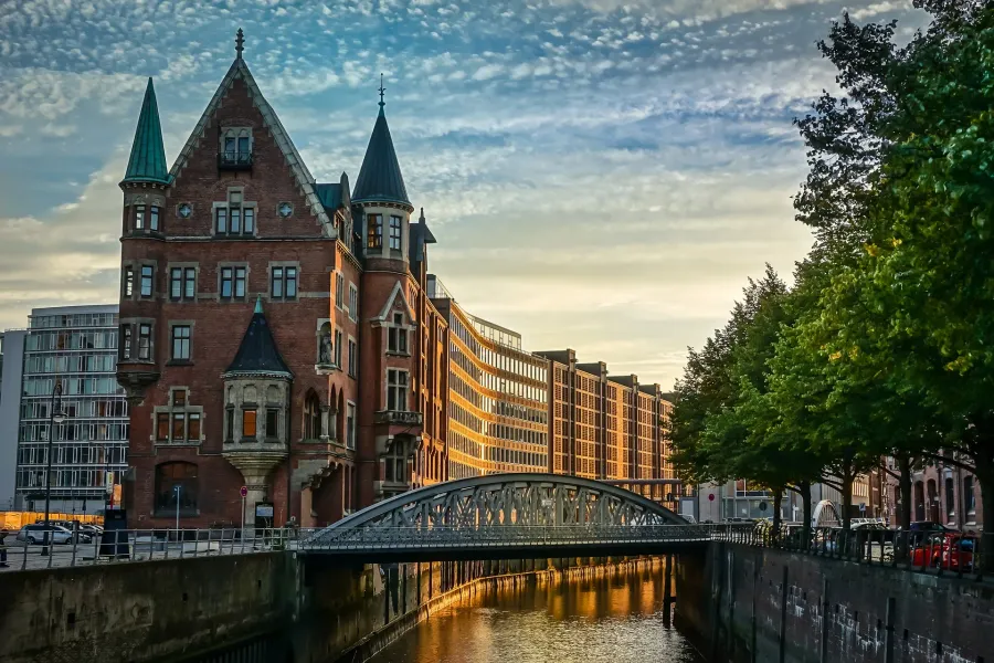 Sunset view of a charming canal in Hamburg, Germany, with a unique brick building and bridge.