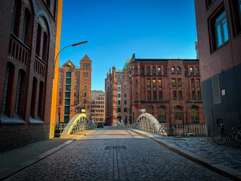 Cobblestone street in Hamburg, Germany, leading to a bridge with historic brick buildings.