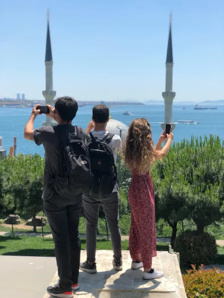 Tourists taking photos of a beautiful mosque and the Bosphorus in Istanbul.