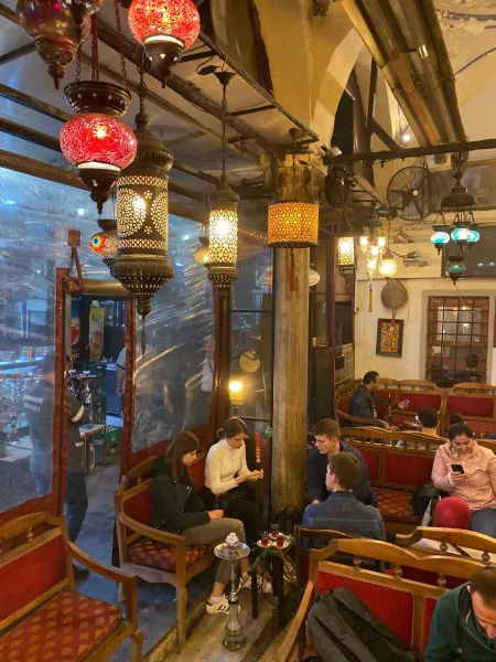 Cozy Istanbul tea house with ornate lamps and patrons enjoying tea.