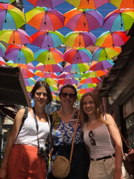 Happy tourists posing under a colorful umbrella street in Istanbul.