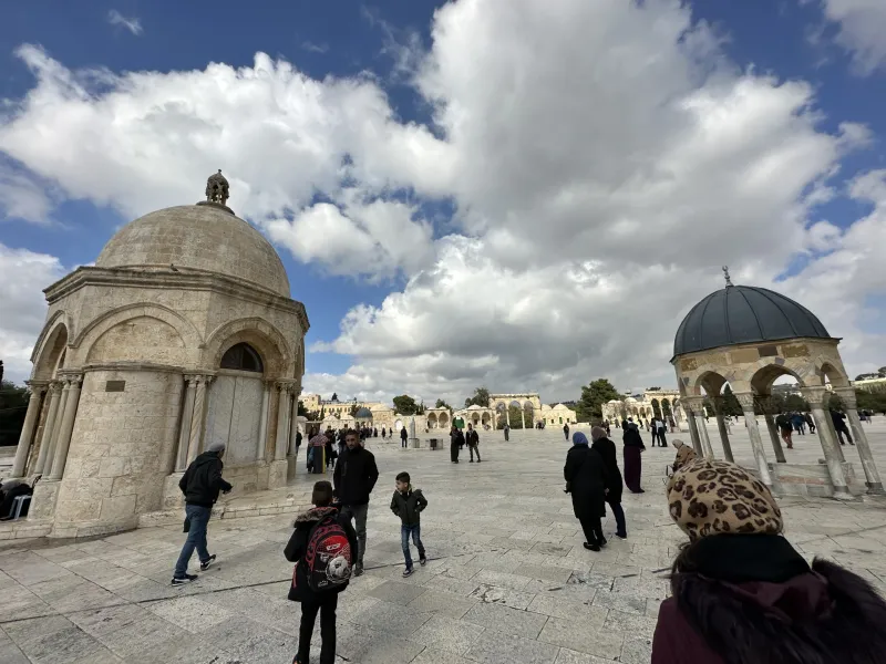 Visitors explore the Temple Mount in Jerusalem, admiring the historical domes and architecture.