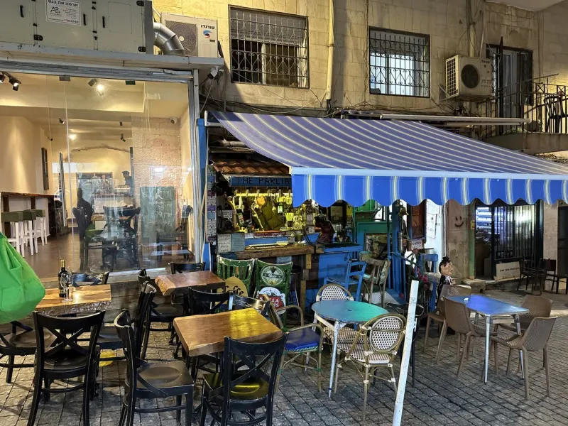 Outdoor seating area of The Parliament bar in Jerusalem at night.
