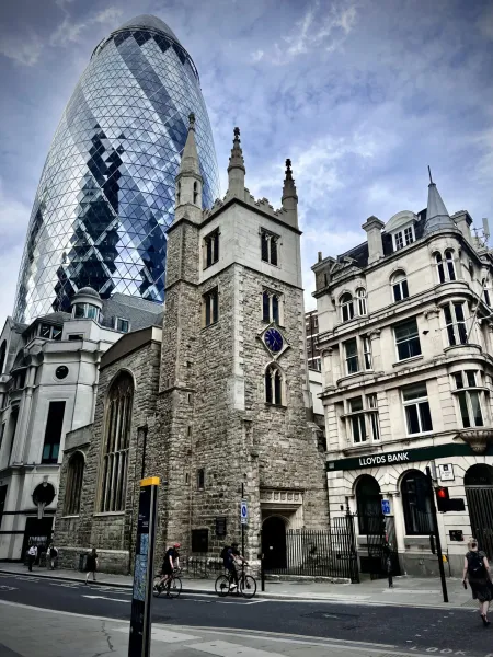 Modern and historic London architecture: The Gherkin, a church, and Lloyds Bank.