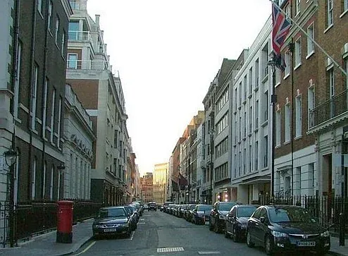 A tranquil street in London, England, lined with elegant buildings and parked cars.