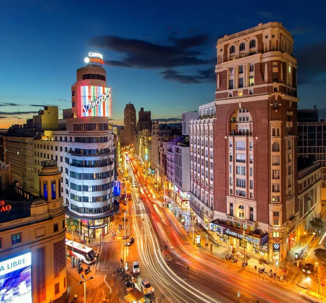 Night view of Madrid's Gran Vía, showcasing its vibrant architecture and bustling street life.