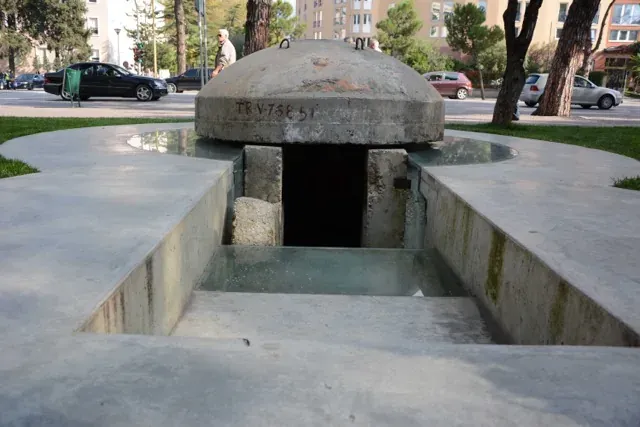 A preserved WWII bunker in a Rome park, partially submerged in water.