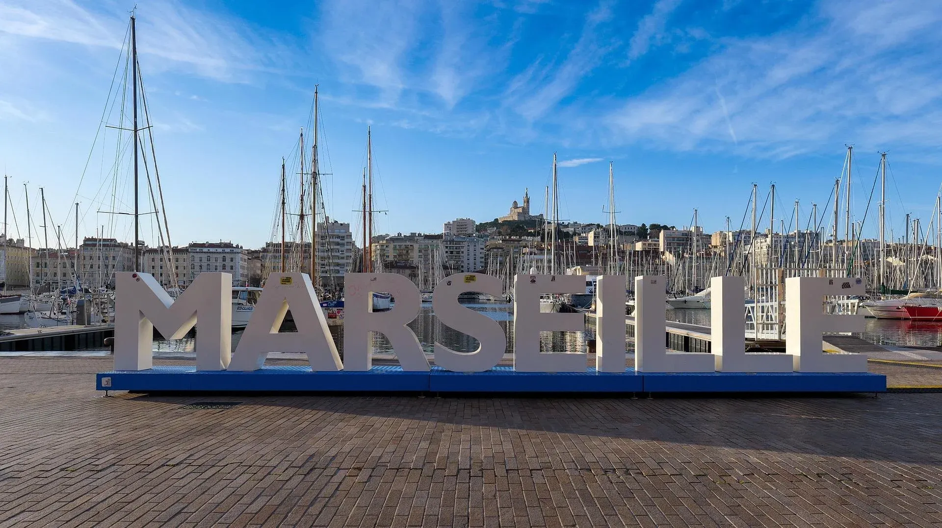 Marseille harbor with sailboats and city sign.