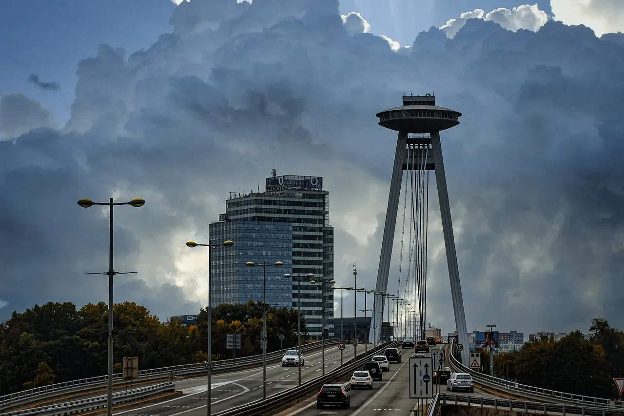 Dramatic view of Bratislava's UFO Bridge and observation tower under a stormy sky.
